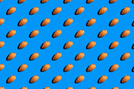 Background from almonds. Trendy sunny pattern of almonds on a bright blue background. Colorful...