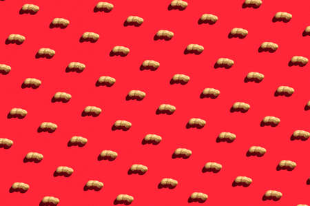 Pattern of peanuts with shell. Fashionable sunny pattern of peanuts with shell on a bright red background. Colorful pattern. View from aboveの写真素材