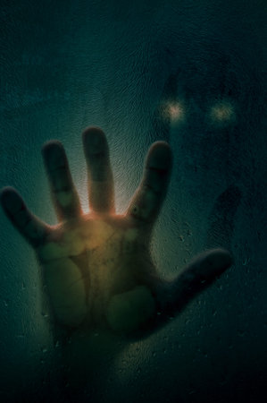 Horror scene of a man with hand against wet shower glass and dark cityscape background. Toned image....