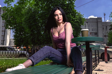 Young woman drinking coffee in the street. Female in the city street drinking a hot beverage. Image...