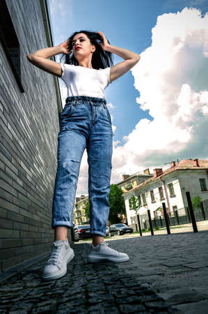Portrait of a young woman outdoors on the background of a building. Young girl near the building. Lifestyle. Gen Z.の写真素材