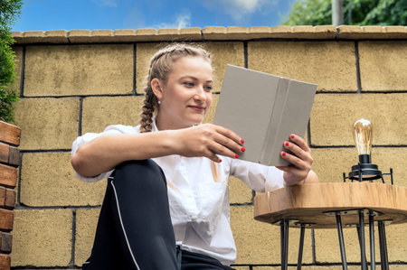 Smiling young woman reading book. Young woman in a cafe