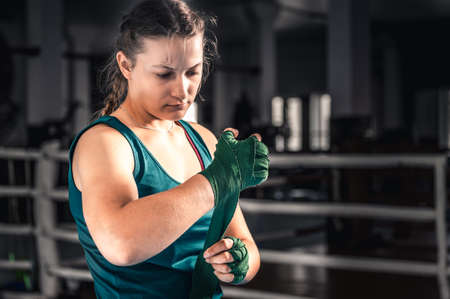 Young woman getting ready for boxing exercise. Woman boxer getting ready near the ringの写真素材