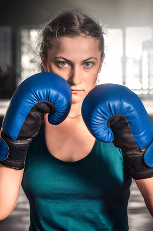 Ð¡lose up view of girl in boxing gloves training at gym. Young woman boxing in the gym. Vertical...