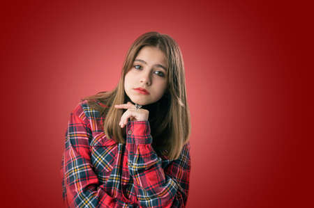 Sad teenage girl on red background. Portrait of sad unhappy teenage girl. Studio shot. Isolated on red background. ...の写真素材