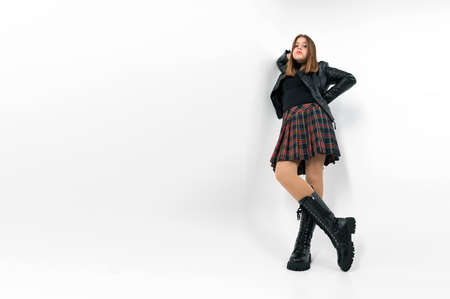 Teenager girl in a skirt posing in the studio on a white background. Full length portrait of a girl wearing plaid skirtの写真素材