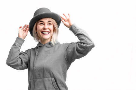 Smiling woman. Beautifu youngl woman wearing gray hat and in a gray sweatshirt. Young woman with beautiful smile happy and excited. white background.の写真素材
