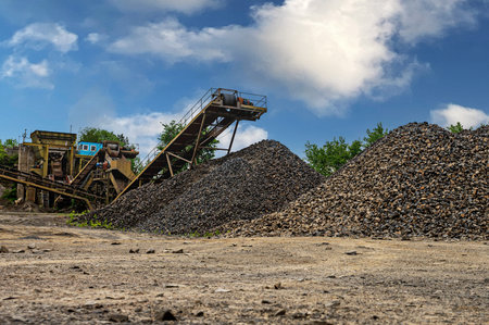 Mining industry gravel quarry conveyor. Crushing machinery, cone type rock crusher, conveying crushed granite gravel stone in a quarry open pit mining.の写真素材