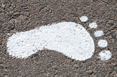 Bare footprint on asphalt. White paint imprint of a human footprint of bare feet on an asphalt road. White foot print.の写真素材