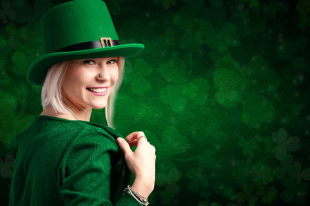 Smiling woman in green attire with leprechaun hat against a clover backdropの写真素材