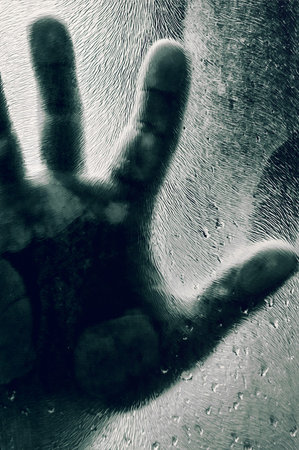 Mans figure with hands pressed against frosted glass. Shadow of a man behind the matte glass blurry...