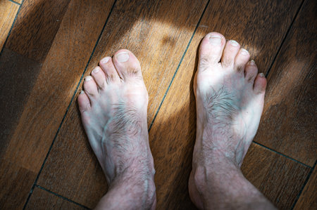 Bare legs of a man. Nude male legs on wooden floor with copy space. Male bare feet, toes with long nailsの写真素材