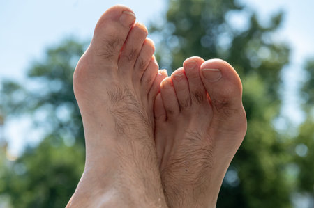Bare legs of a man. Naked male legs sticking out of a window against a background of green nature....