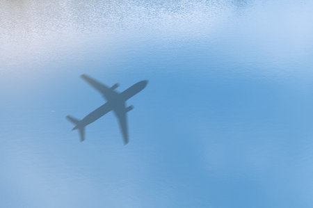 Concept of airplane travel. Airplane shadow on blue water. Aerial view of ocean waves with airplane shadow on the water.の写真素材