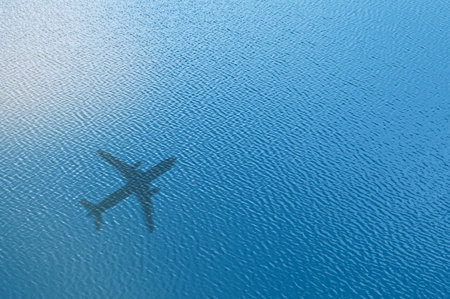 Concept of airplane travel. Airplane shadow on blue water. Aerial view of ocean waves with airplane shadow on the water.の写真素材