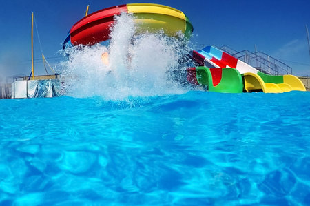 Blue splashes of water against a water park backdrop. Water bubbles. Resort vacation.