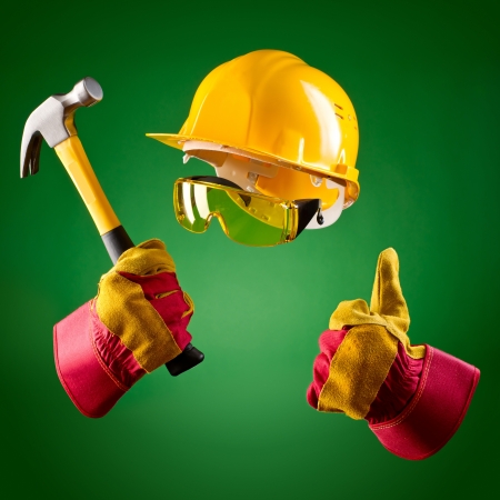 invisible builder in a helmet and with a hammer on a green backgroundの写真素材