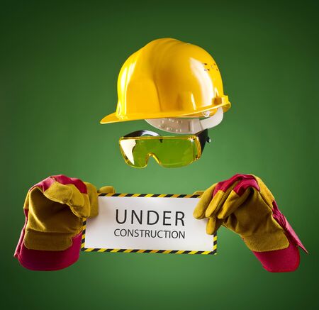 invisible builder in a yellow helmet with an information banner on a green backgroundの写真素材