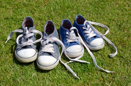 Two pairs of old sneakers on grass backgroundの写真素材
