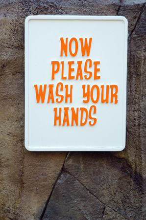 Wash your hands sign on stone wallの写真素材