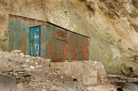 An old rusty shed at the base of a cliffの写真素材