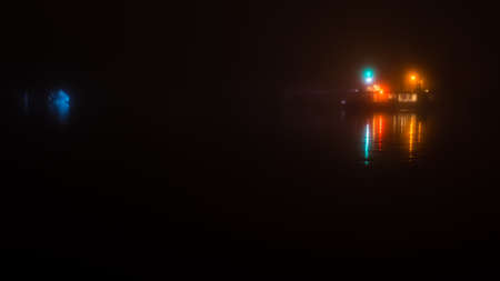 little ferry at foggy night with water reflectionの写真素材