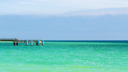 turquoise colored ocean and a pier at a summer dayの写真素材