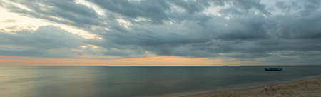 The smooth sea with a lonely boat at morningの写真素材