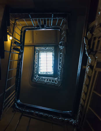An old stairway in the dark with a ceiling lightの写真素材