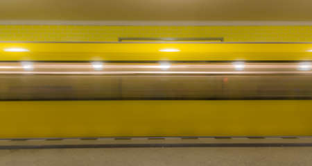 The yellow blurred underground train enters the subway stationの写真素材