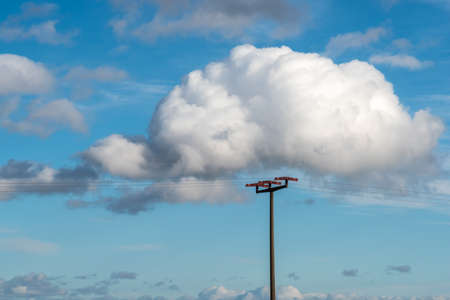 The cloud in the blue sky surrounds the power poleの写真素材