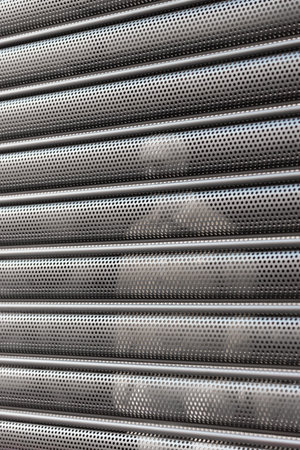 A person stands behind an aluminum roller door