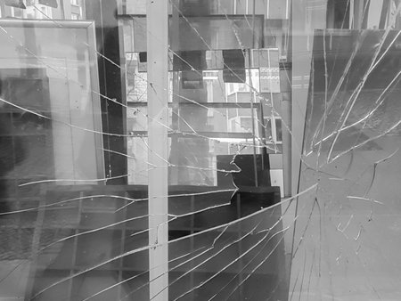 A broken glass of a window with many glass plates in the background in black and white