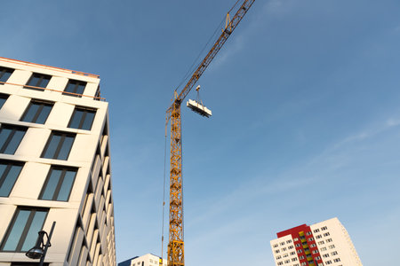 Construction crane with building materials in the middle and on the left a new buildingの写真素材