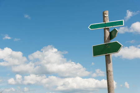 Green signpost with blue sky and white clouds in backgroundの写真素材