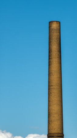 Old chimney of a farbrick with blue sky in backgroundの写真素材