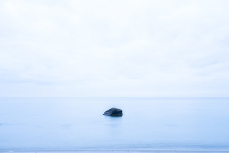 A solitary rock in the sea in a soft blue colourの写真素材