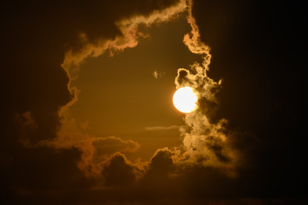 The sun behind a window of thick cumulus cloudsの写真素材