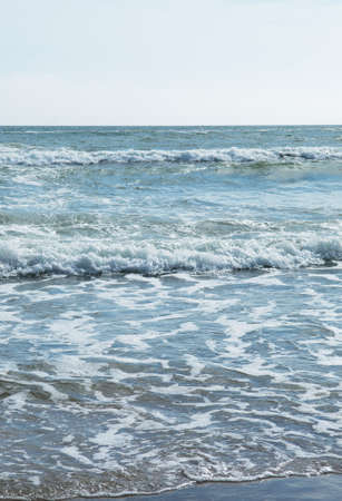 small wave gently swapping on  beach. in the background a great water landscape is taking place.の写真素材