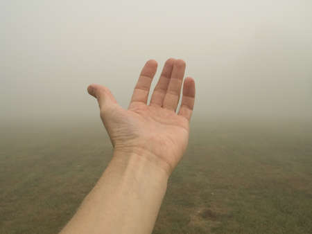 This is a shot of a hand reaching out against a foggy background.の写真素材