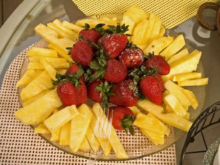 A platter of fresh strawberries and cut pineapple.の写真素材