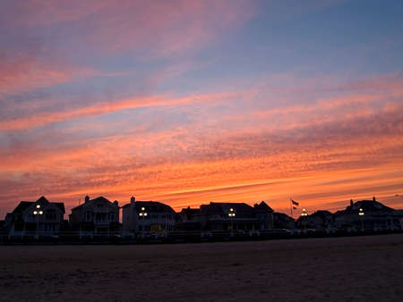 A dramatic sunset and the dark contrast of homes along the beach in the town of Avon by the Sea in New Jersey.の写真素材