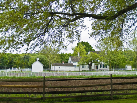 A farm fence and Spring trees frame this historic farmhouse in Holmdel Parkの写真素材