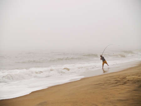 A young fisherman casts into the sea at Sandy Hook in New Jerseyの写真素材