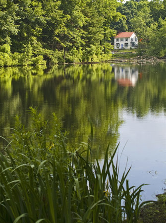 A home off in the distance on a small lake reflecting with the trees upon the water in this quiet...