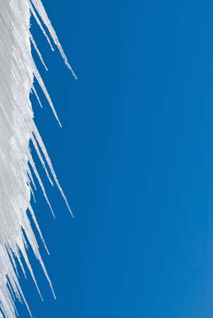 Icicles background photo against a bright blue sky.の写真素材