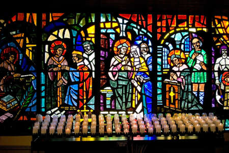 Stained glass windows and votive candles in a catholic church.の写真素材