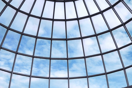 A glass dome with a cloudy blue sky on the ceiling of this modern building.
