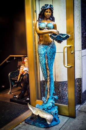 A metal mermaid statue on the sidewalk in Manhattan.のeditorial素材