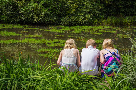 HAMILTON TOWNSHIP NEW JERSEY  MAY 9: Three children look into a pond at the Azalea Festival on May 9 2015 in Hamilton Township New Jersey.のeditorial素材